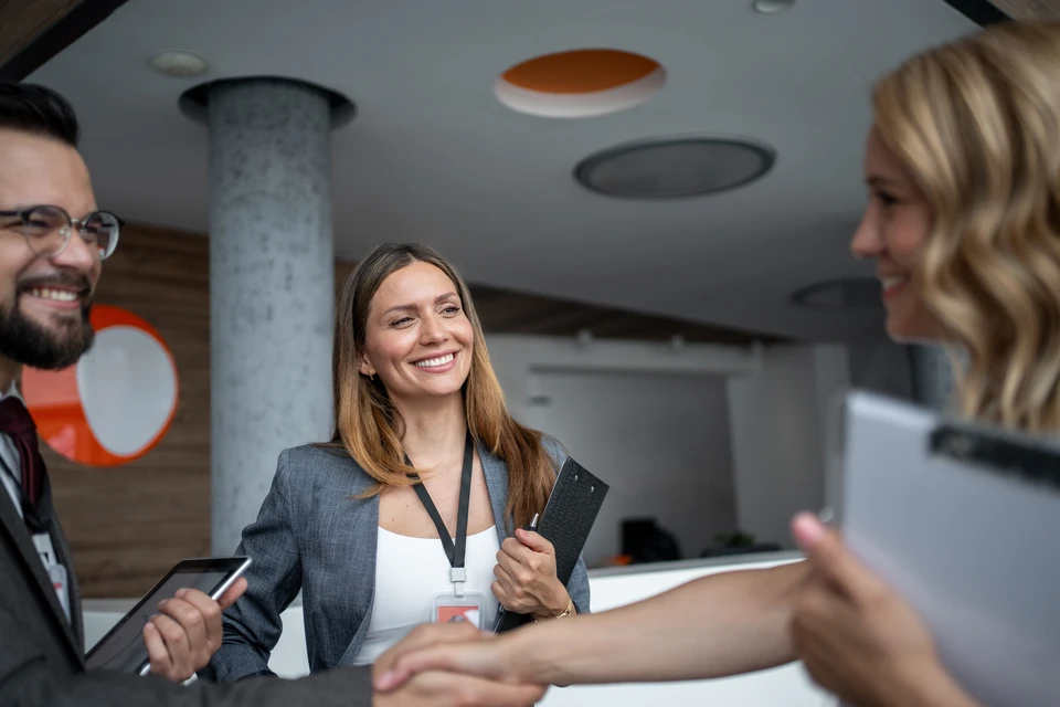 Homme d'affaires en chemise blanche et cravate noire, lunettes, assis à un bureau en bois clair, menton appuyé sur les mains croisées, expression pensive
