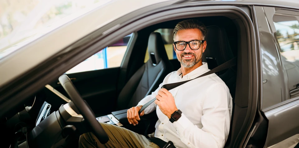 Photographie montrant trois conducteurs de profils variés (jeune conducteur, conducteur d'âge moyen, conducteur senior) se tenant debout à côté de leurs véhicules respectifs (voiture citadine, monospace familial, berline), dans un contexte de stationnement ensoleillé. Les personnes doivent afficher une expression naturelle et confiante, sans sourire excessif. L'image doit clairement montrer la diversité des profils de conducteurs et leurs véhicules distincts, illustrant ainsi que chaque conducteur a des besoins spécifiques en matière d'assurance automobile.