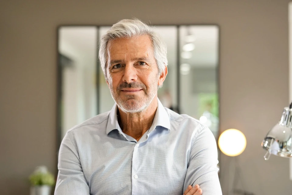 Homme d'affaires en costume sombre debout face à un mur, dos tourné, contemplant deux flèches blanches peintes pointant dans des directions opposées, symbolisant un choix stratégique ou une décision cruciale